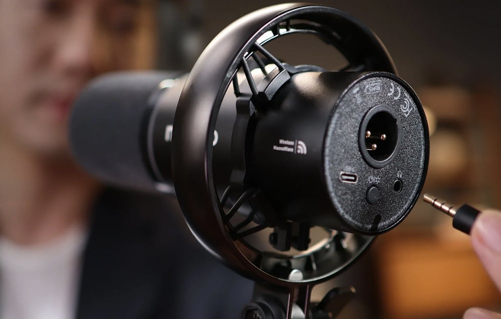 A close-up of the bottom panel of the Maono microphone with an XLR and USB-C port and a 3.5 mm jack plug approaching