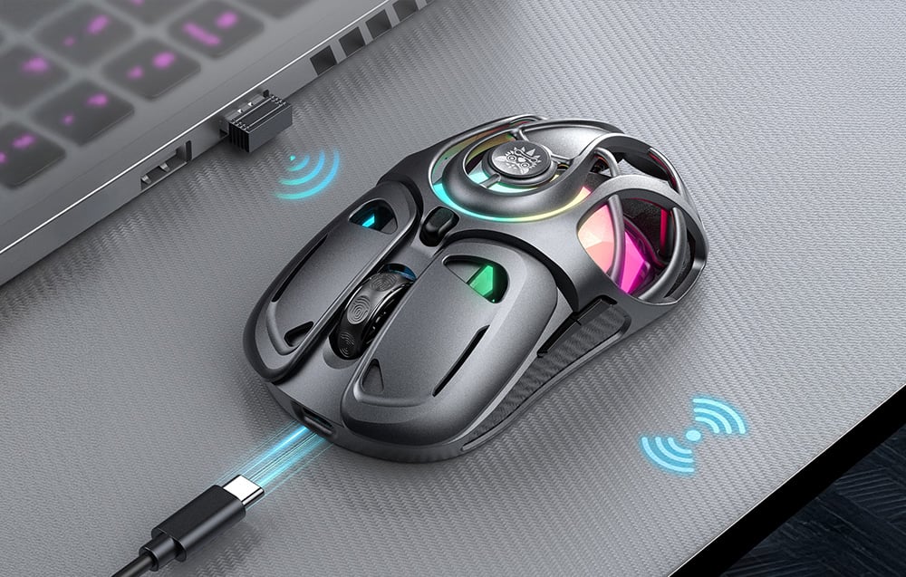 Black gaming mouse on desk next to laptop with receiver and cable