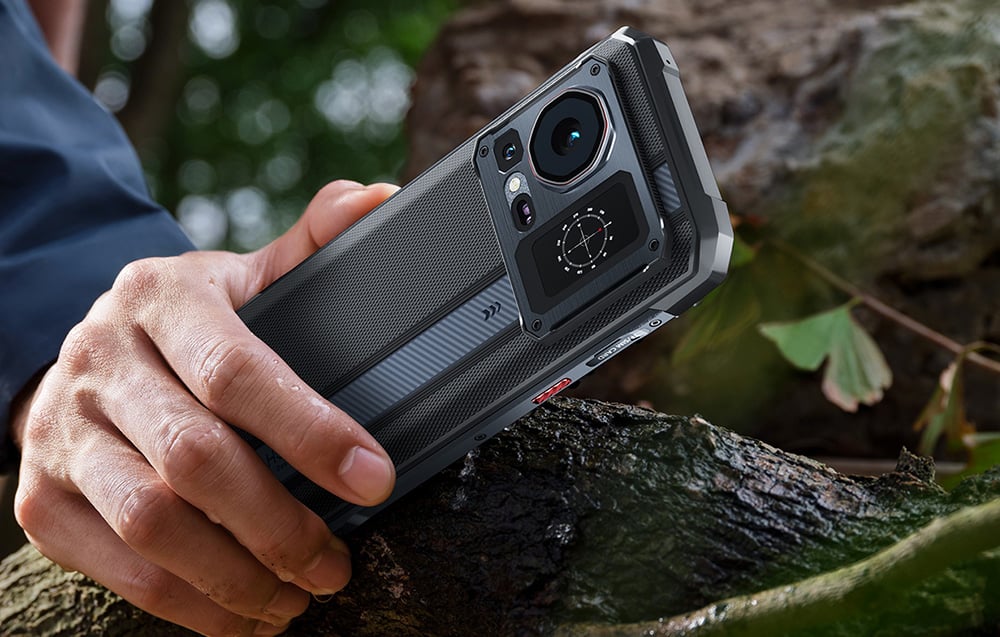HOTWAV smartphone held in the hand next to a tree trunk, with the compass visible on the rear screen.