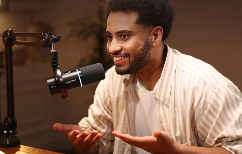 A man in a light-colored shirt speaks into the maono microphone