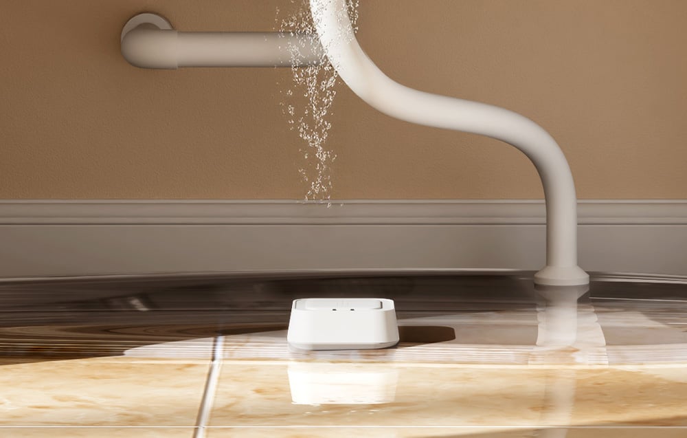 MEROSS Smart Water Leak Sensor placed on the floor under a leaking pipe