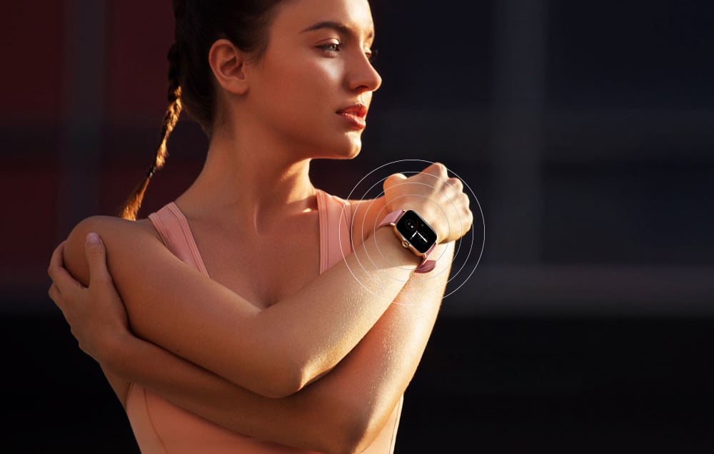 A woman in a pink sports outfit during a workout, with a smartwatch visible on her wrist