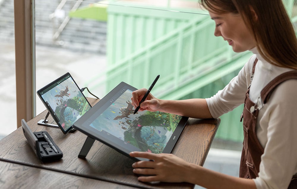 Woman drawing on Huion tablet with additional monitor showing work
