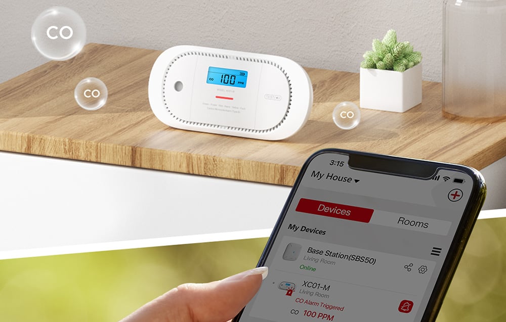 Detektor CO na drewnianej półce z symbolami CO w powietrzu i telefon z aplikacją pokazującą alarm