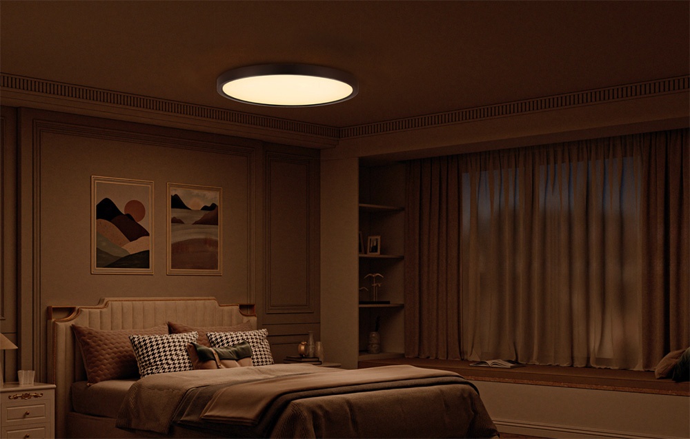 Yeelight Meteor C500 ceiling lamp shining in a darkened bedroom with beige bedding and pictures above the bed.