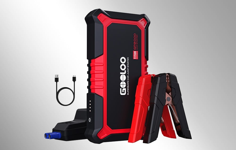 Car jump starter with clamps and a USB cable on a light background