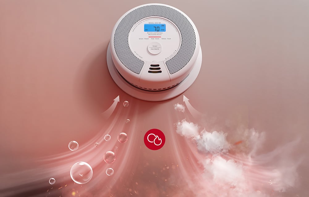 A close-up of a carbon monoxide and smoke detector with an LCD display, into which smoke and gas particles are entering