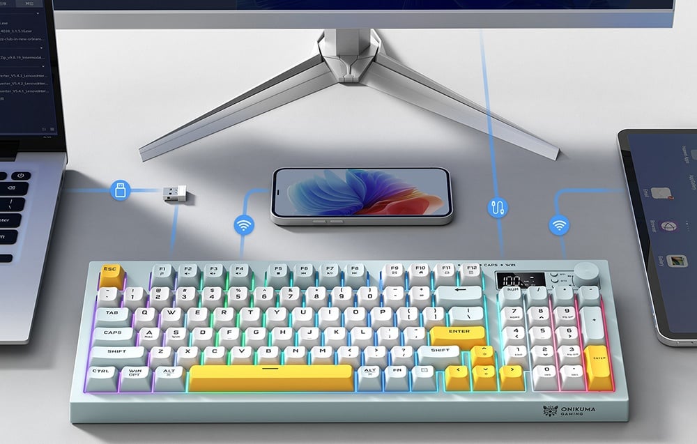 Pastel colored keyboard on desk with laptop, smartphone and monitor