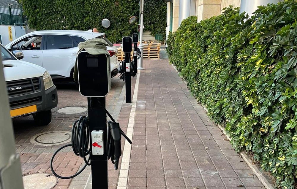 A freestanding electric car charging station located near outdoor parking spaces.