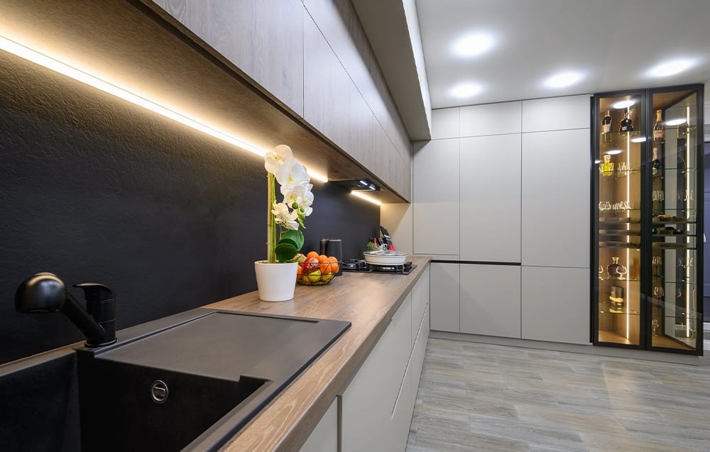 Modern kitchen with black sink, wooden countertop and LED lighting under the cabinets