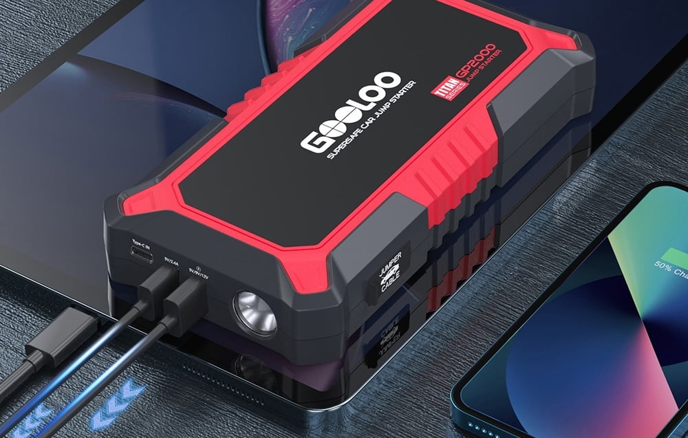 Car jump starter charging mobile devices connected by cables on a desk