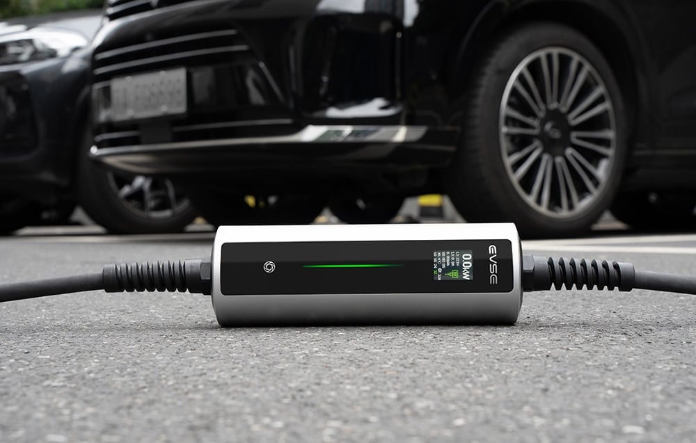 The EV charger is lying on the ground, with parked cars in the background