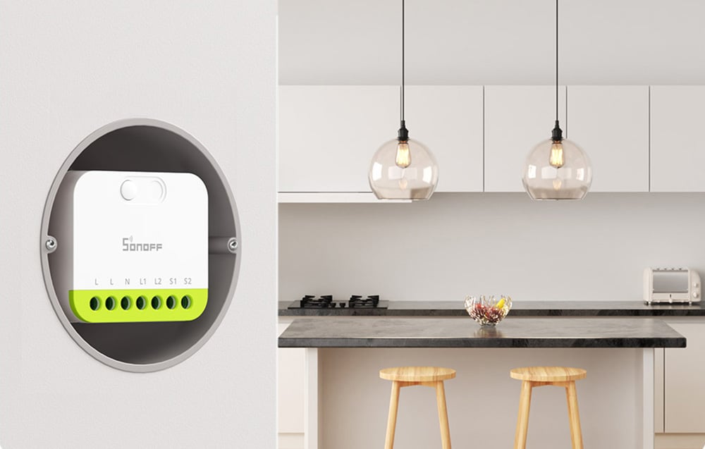 Sonoff smart switch mounted in a wall box next to a modern kitchen with two pendant lights