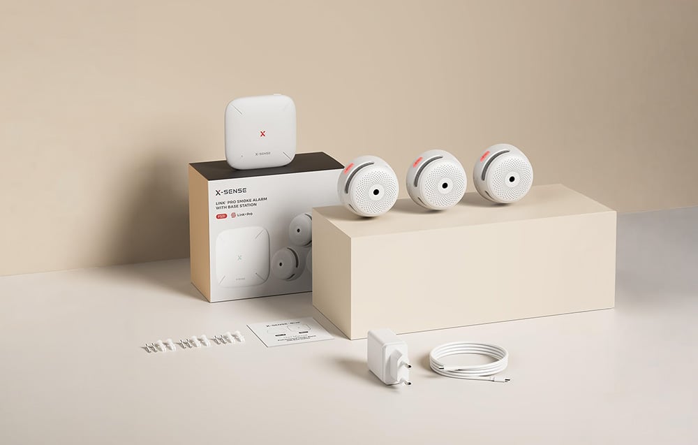 X-Sense product set with three smoke detectors, a base station, a box, a manual, and mounting accessories