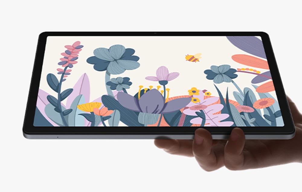 Hand holding tablet with pastel illustration of flowers, butterflies and plants on white background