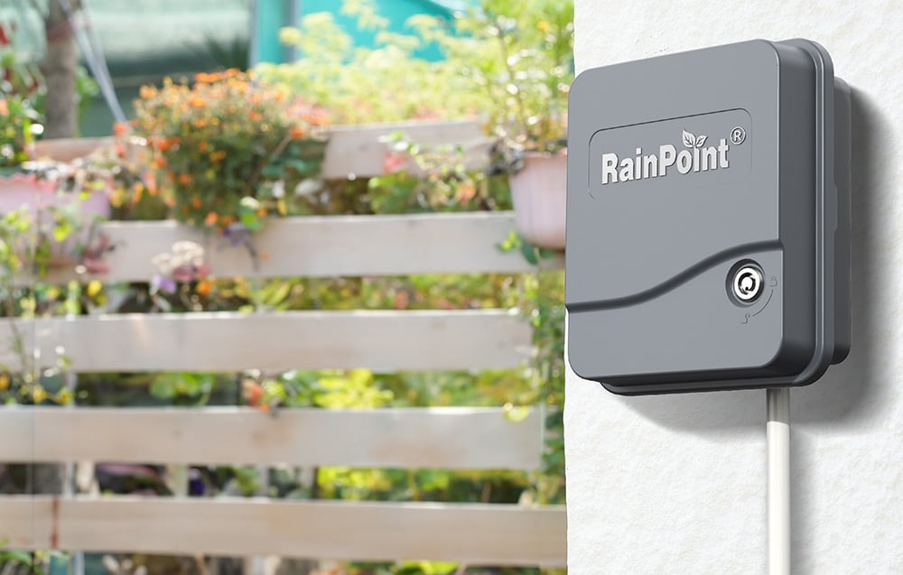 Closed RainPoint controller mounted on the wall with a view of the garden in the background.