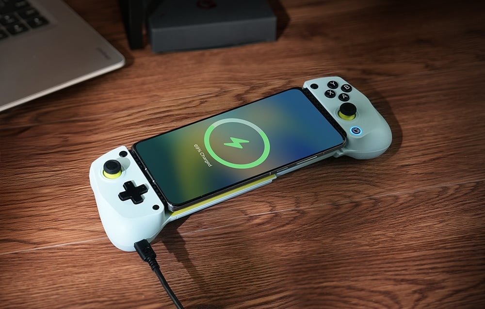 A smartphone charging in a GameSir controller mounted on a wooden surface.