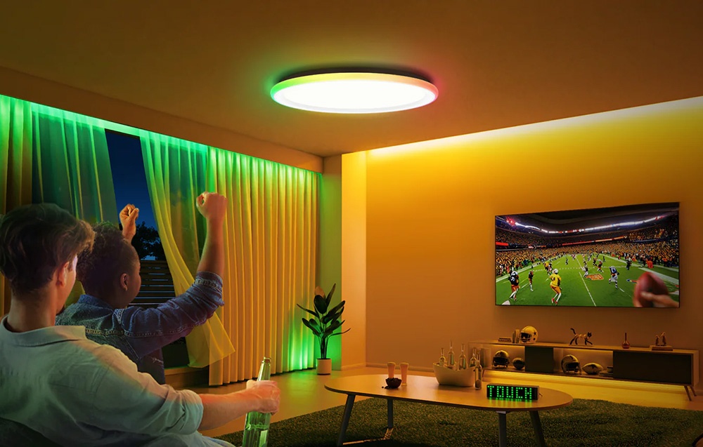 Two men watching a game in the living room illuminated by the Yeelight Mars C300 lamp in green and yellow.