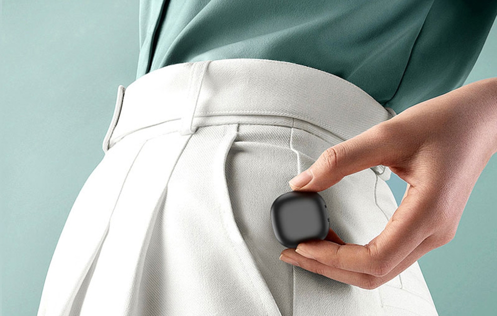 A woman in white pants puts a small black smart ring case into her front right pocket