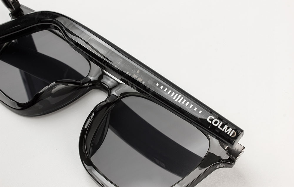 Close-up of black Colmi glasses on a gray background