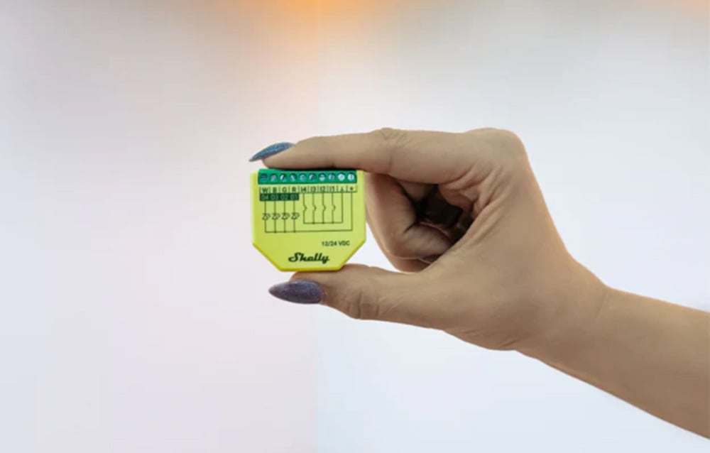 Yellow Shelly LED strip controller held in hand against a gray background