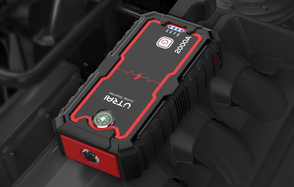 The Utrai jump starter resting on a car engine, showing the built-in flashlight on the front panel.