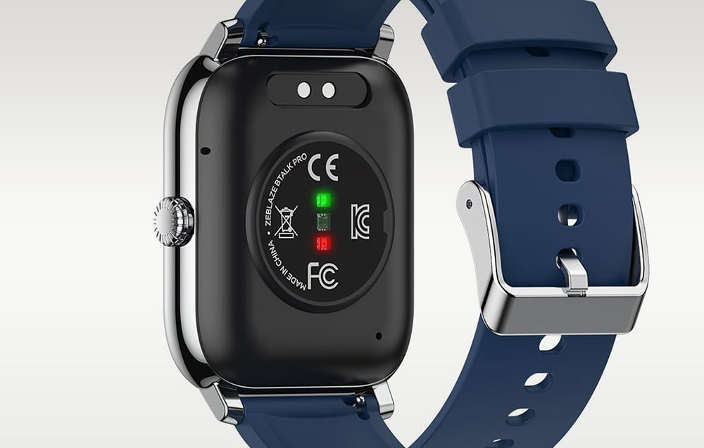 The back of the smartwatch case showing sensors, charging contacts, and a navy blue strap with a metal buckle