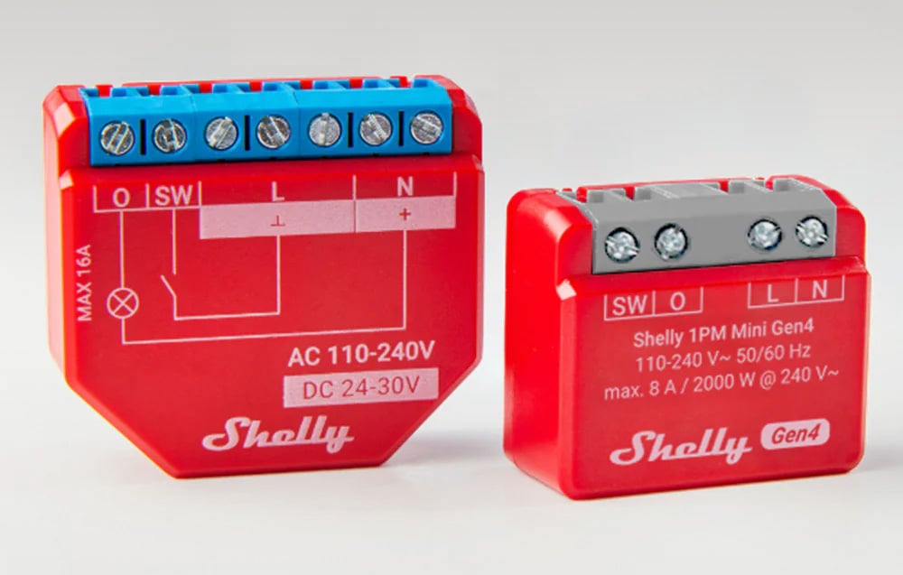Two red Shelly controllers of different sizes side by side on a light background. Circuit diagrams and blue terminals are visible.