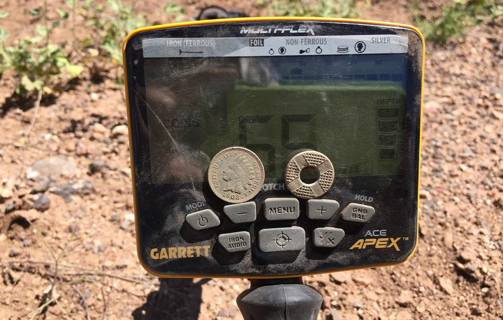 Metal detector panel with visible coins arranged on screen.