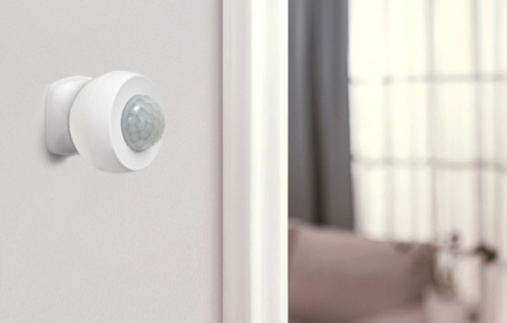 White motion sensor mounted on wall in bright living room