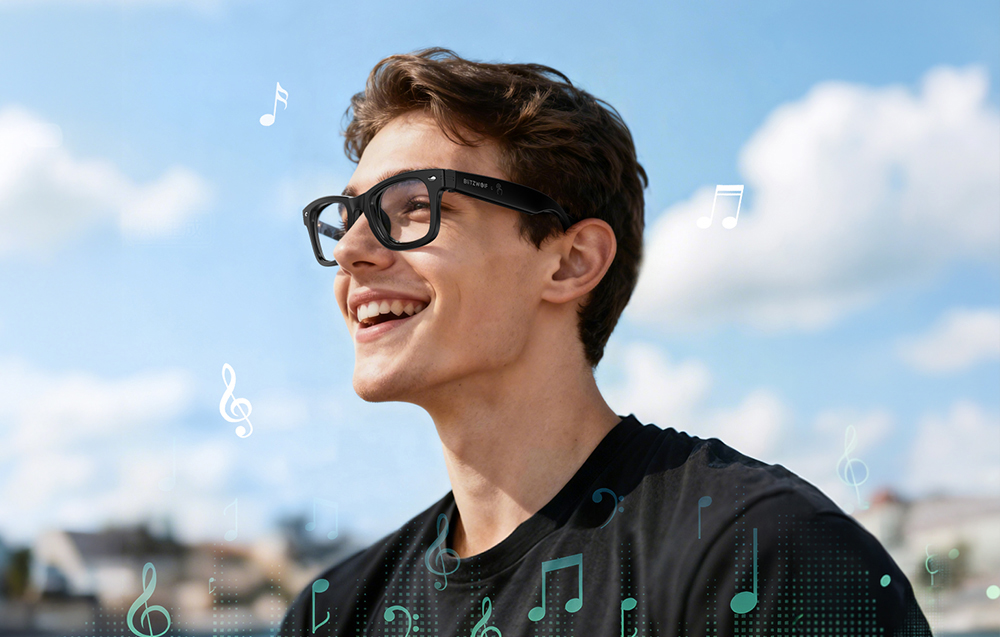 A smiling man in a black T-shirt and sunglasses, with a blue sky in the background