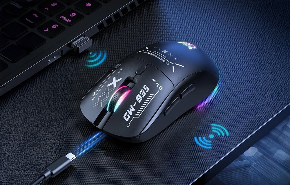 Black mouse on a dark tabletop next to a laptop with receiver and USB-C cable