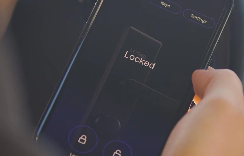 A hand holds a smartphone displaying the word “Locked” and padlock icons on a dark screen background