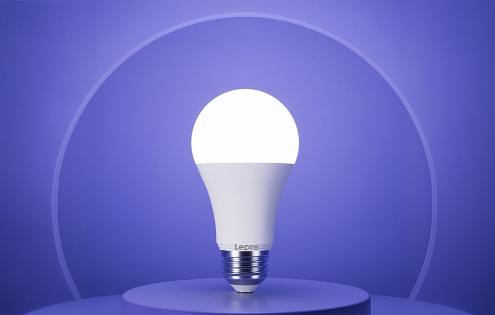 A glowing white LED bulb placed vertically on a round platform, against a smooth purple background.