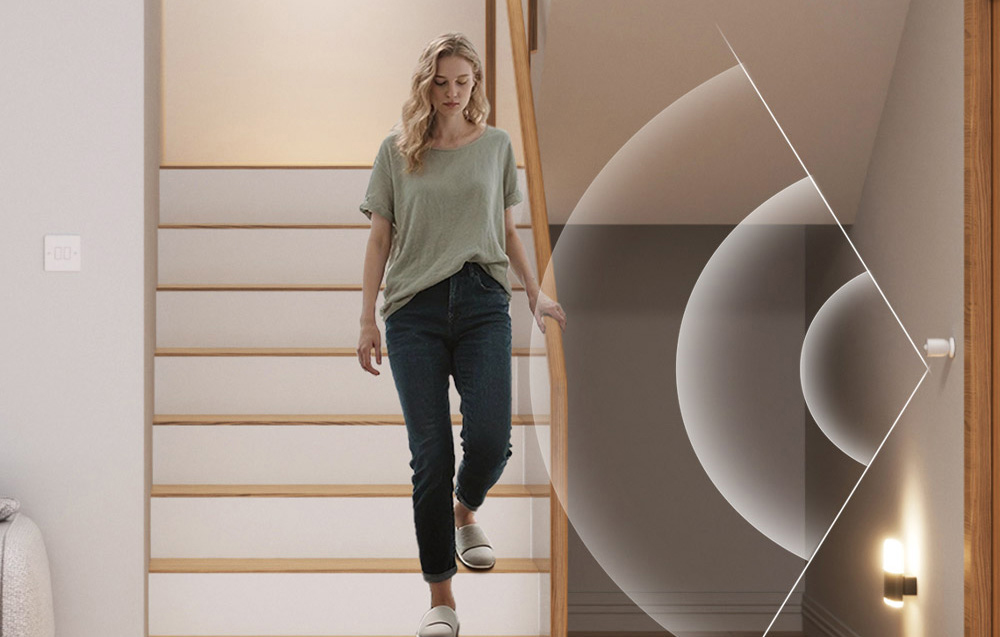 A woman walks down the stairs in the house, next to visualize the operation of the motion sensor