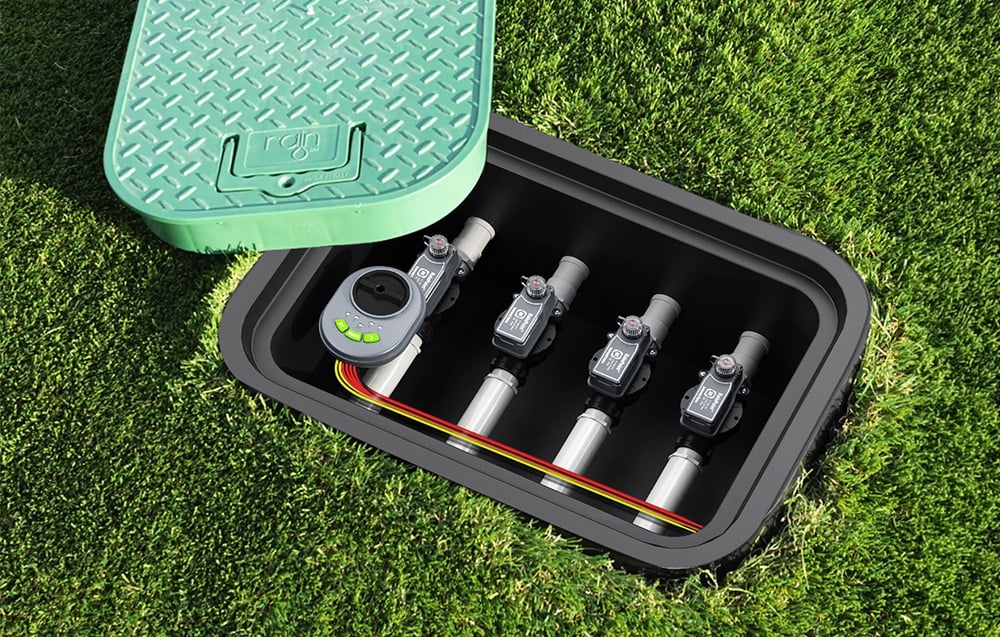 A black box buried in the lawn with an open green cover bearing the word