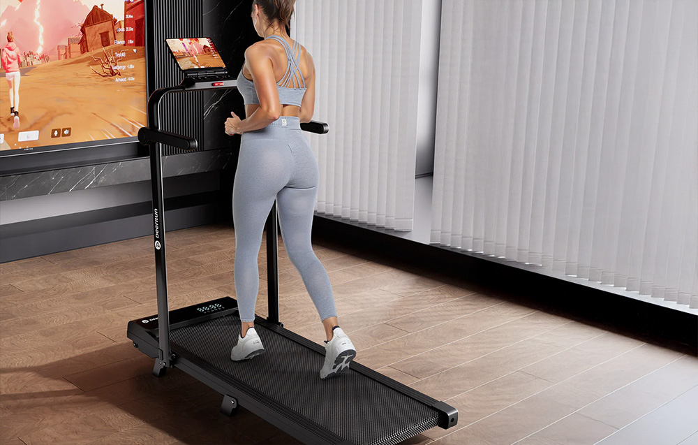 Woman in gray leggings running on a black treadmill while viewing a virtual route on the screen