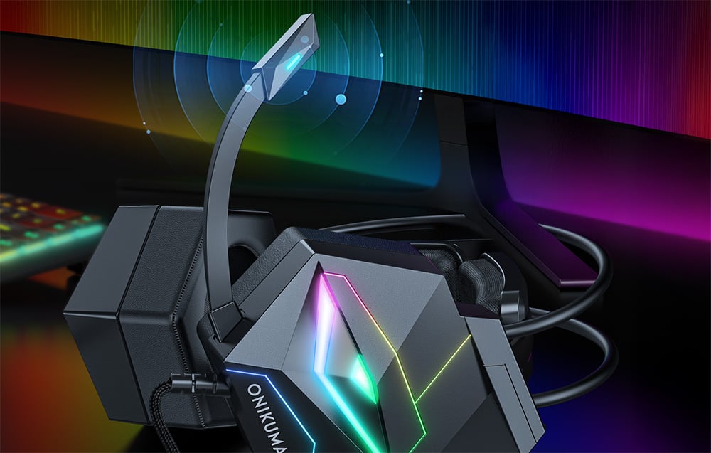 Close-up of the microphone on over-ear headphones lying next to a monitor and keyboard