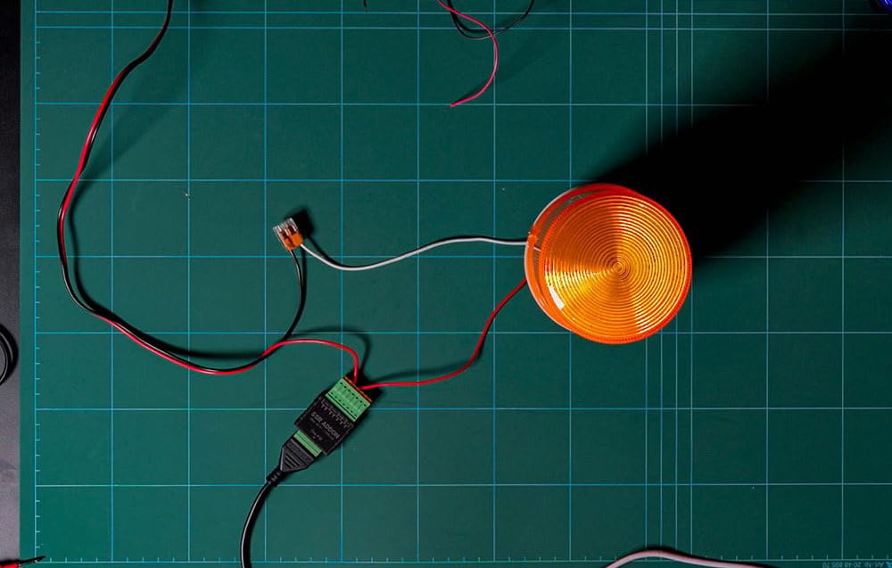 An orange warning light connected by wires to the ADDON SSR module and a Wago connector on a green mat