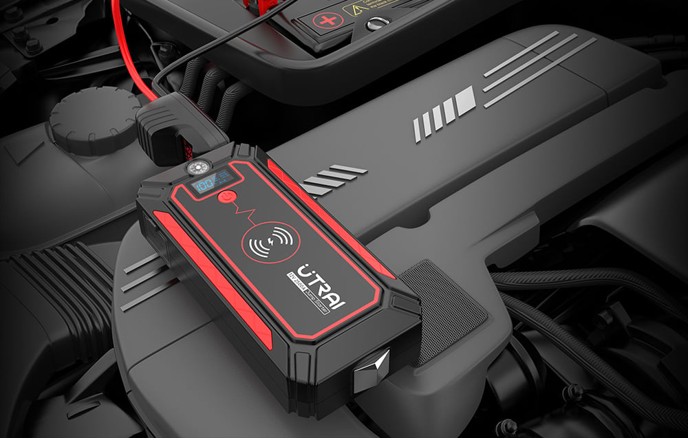 A black car jump starter with red accents resting on the engine under the hood of a vehicle.