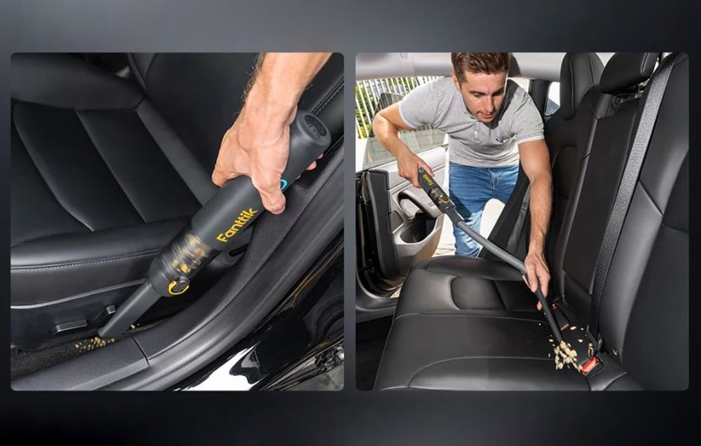 A man removes dirt from a car couch with a portable car vacuum cleaner.