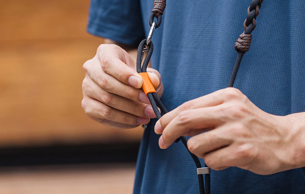 The person in the blue shirt adjusts the length of the PGYTECH strap