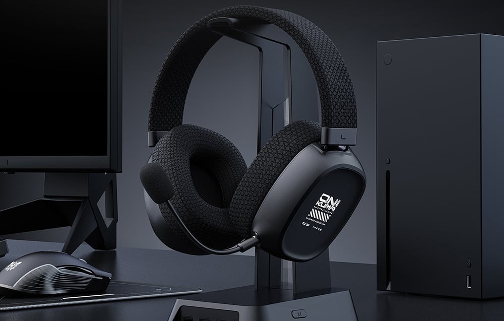Black gaming headphones on stand next to console and monitor on desk