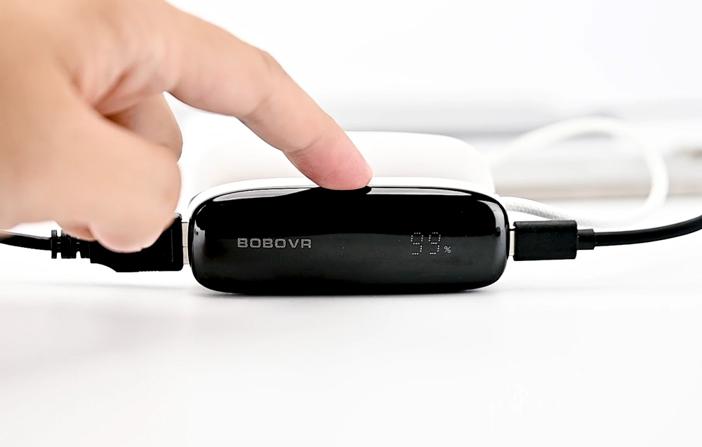 Close-up of a hand pressing a button on the BoboVR PD100 model.