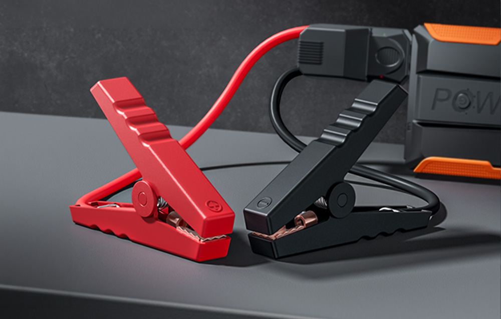Two car starter terminals—red (positive) and black (negative)—lying next to the device.