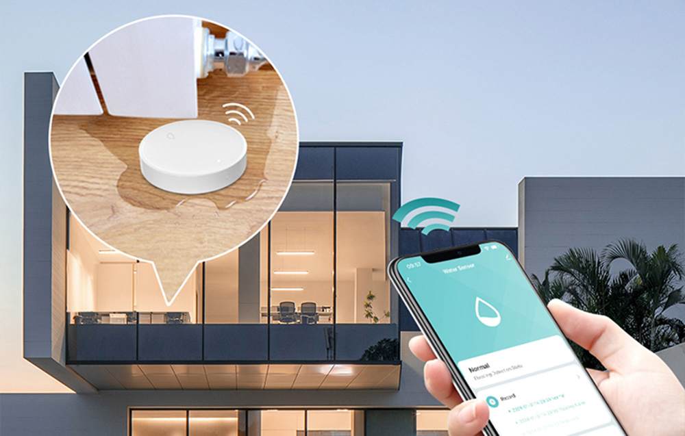Smartphone with app for flood sensor on the background of the house, with zoom showing the sensor on the floor under the pipe