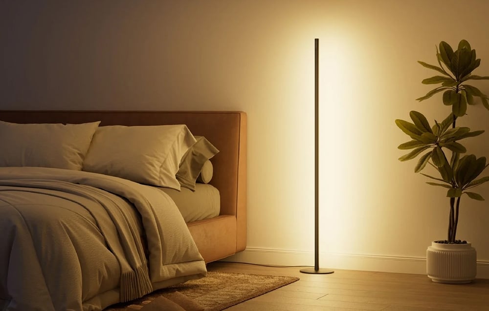 Minimalist LED floor lamp in the bedroom next to the plant, warm yellow light by the bed
