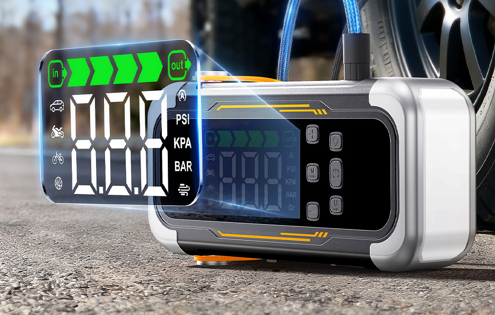 A car starter motor with visible screen graphics stands on the road next to a vehicle’s wheel.