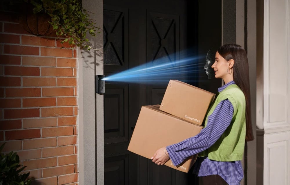 Woman with boxes recognized by biometric system - a blue ray scans her face at the door