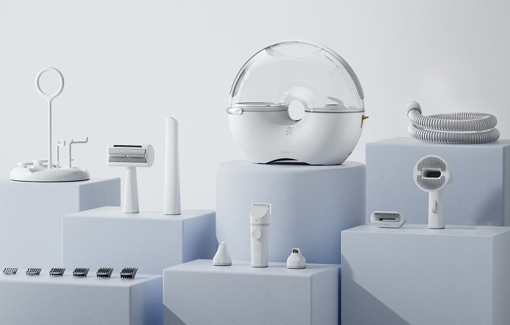 A transparent round chamber with a vacuum cleaner hose stands on a white podium next to other accessories